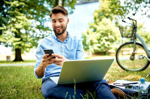 Man efficiently using AI grading software on a laptop with a smile, while happily discussing results on a phone